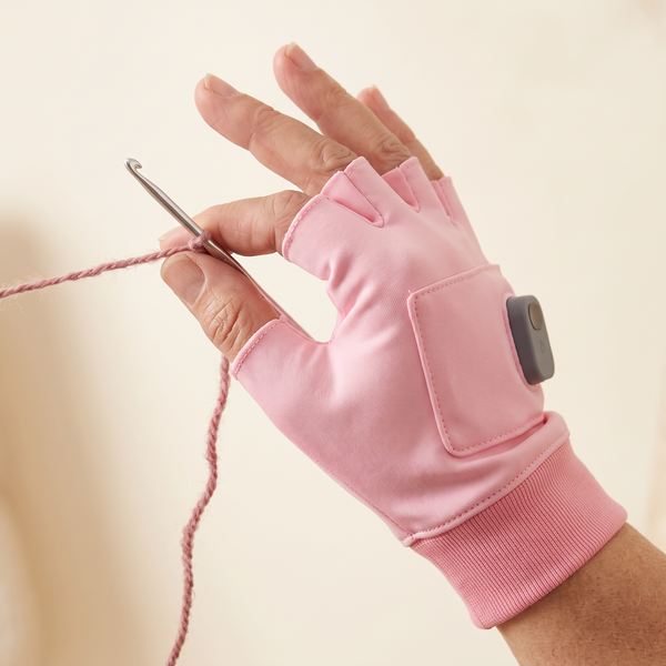 Fingerless heated glove holding a crochet hook and yarn
