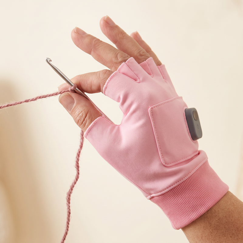 Fingerless heated glove holding a crochet hook and yarn